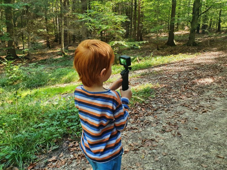 Ein Kind trägt eine GoPro im Wald und filmt.